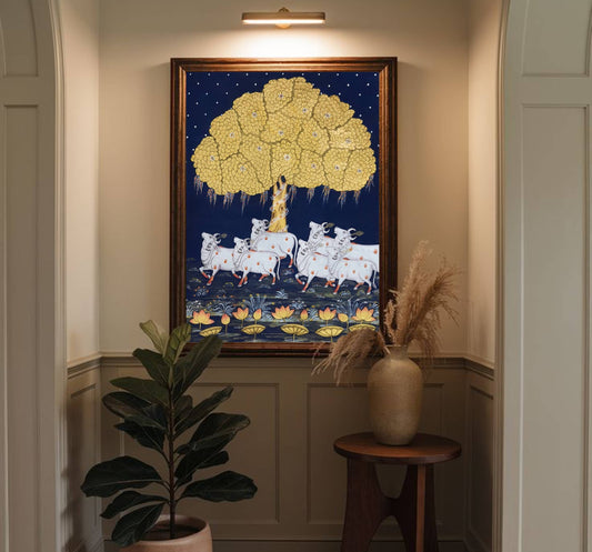 Decorative wall art with a gold tree and white animals in a room with a plant and vase.