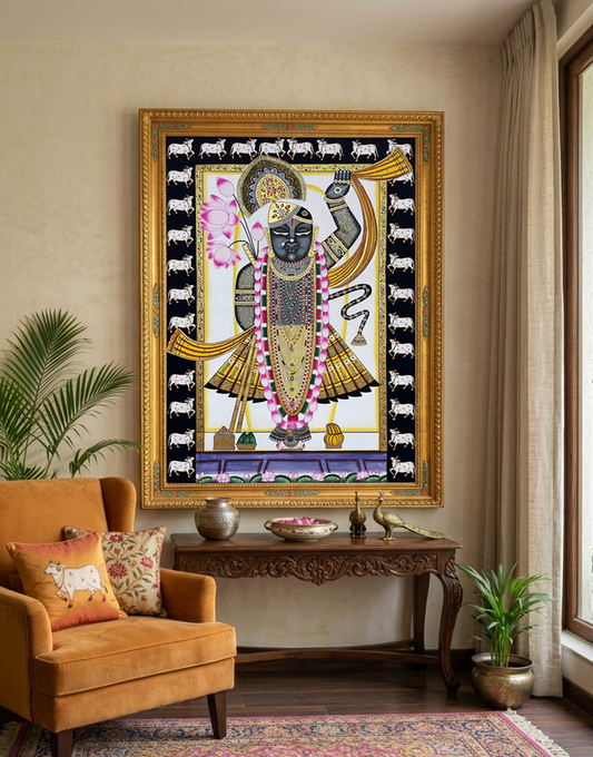 A beautifully framed Pichwai painting of Shreenathji is displayed on a wall, showcasing vibrant colors and intricate details.